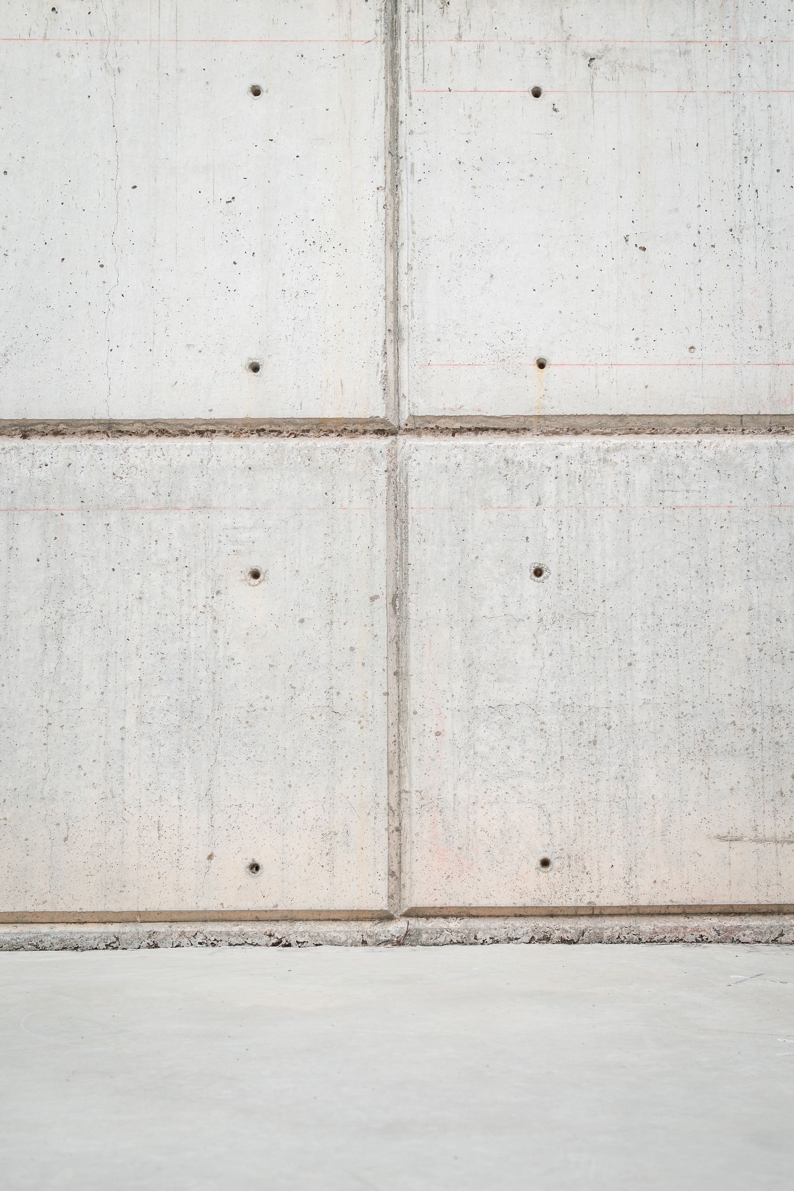 Mur de béton coulé montrant des rangées de trous de tiges de coffrage alignés